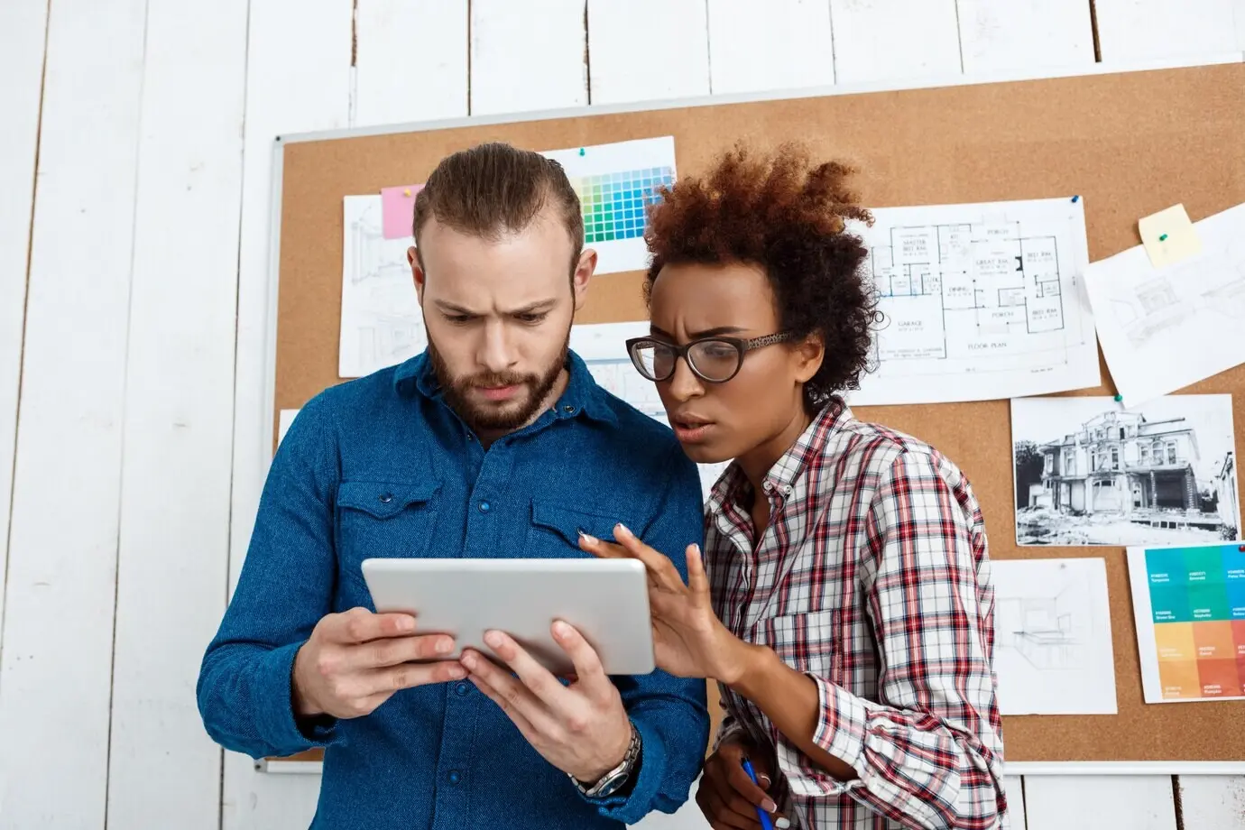 Kollegen schauen auf ein Tablet und besprechen neue Ideen.